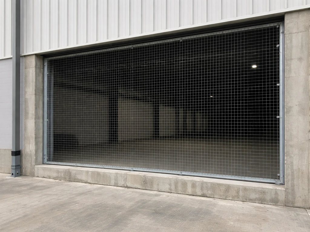 Wire mesh sealing a warehouse loading-dock opening to prevent roosting near access points.